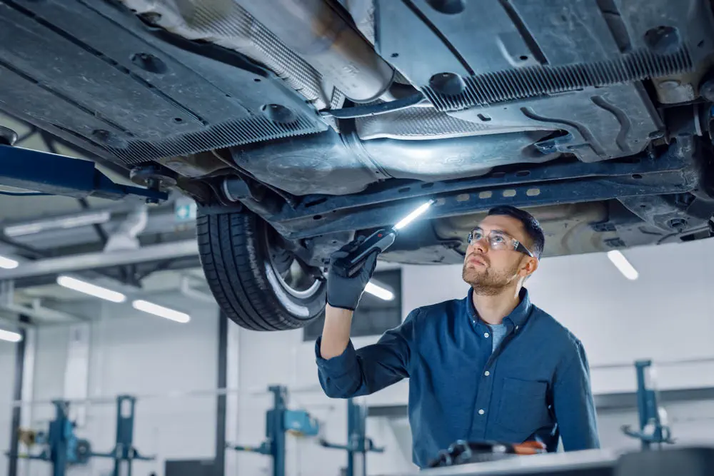 hübscher professioneller Automechaniker, der Rost untersucht